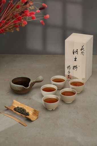 an arrangement of  cups with tea and one teaspoon next to a bowl