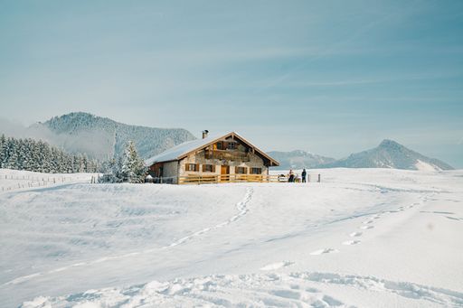 A scenic snow-covered landscape featuring a small log cabin in the distant background