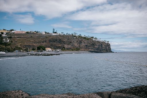 A scenic beach view with buildings overlooking the ocean from a rock break, La Gomera, Canary Islands