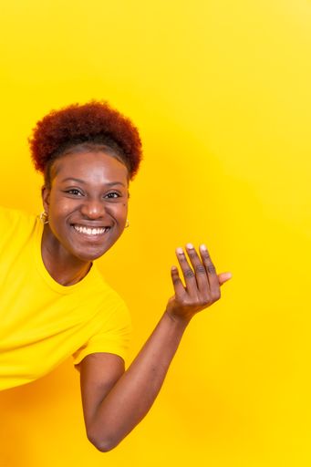 A portrait of a young cheerful black woman doing an inviting gesture