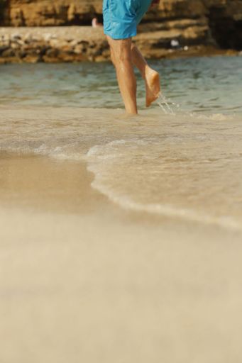 A male walking on the beach shore