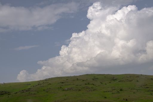 A grassy hill against a cloudy sky