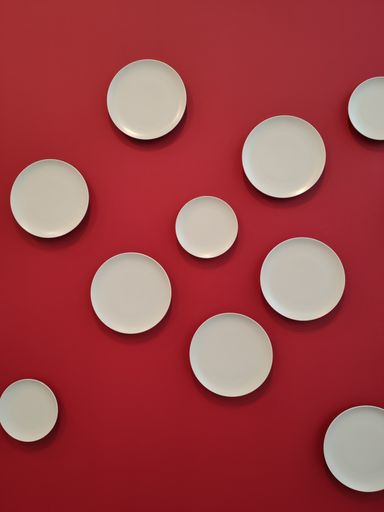 A vertical shot of white plates on a red wall decorated on a cafe