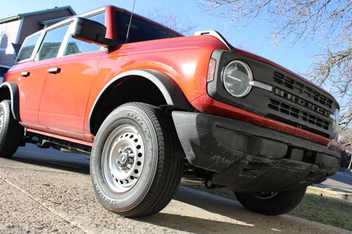 A low angle of an orange-colored vehicle parked on a curb on the street