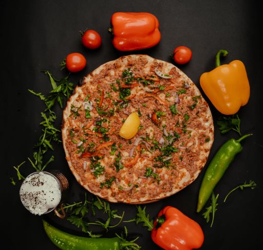 A top view of a Turkish Pizza on Big Serving Plate With Rice and Salad, decorated with peppers