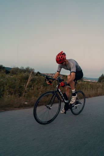 A young adult male is cycling along a rural road