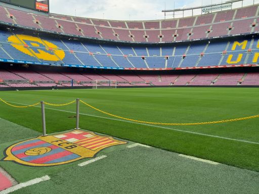 a soccer stadium with a lush green grass field, emblazoned with the crest of Football Club Barcelona