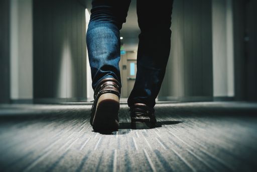 A closeup shot of a male wearing jeans and walking in a hallway - cool background