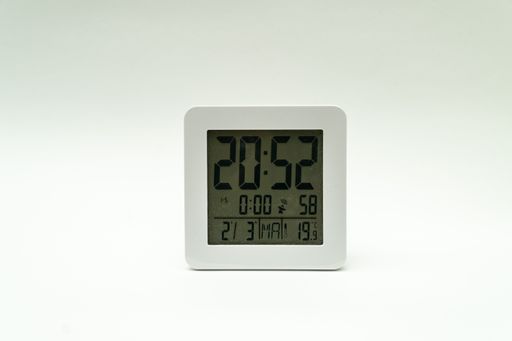 A closeup shot of a plain white alarm clock showing the time on a clean white background