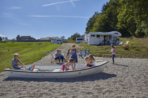 Group of toddlers and their parents playing and enjoying on natural playground near the lake.