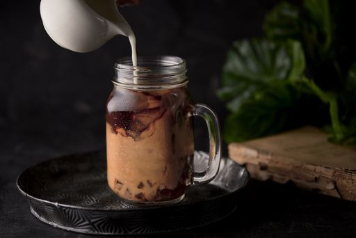 A shot of a hand pouring milk in a jar with coffee