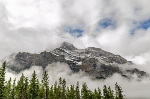 A beautiful mountainous landscape with trees under a cloudy sky in Banff National Park, Canada