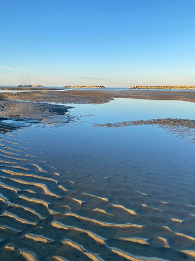 A tranquil lagoon showcases the beautiful blue sky, with the still waters providing a reflective and calming surface