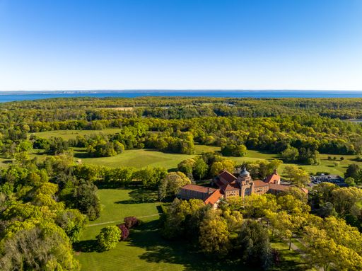 An aerial view over a large seminary and retreat on Long Island, New York on a sunny day, surrounded by a beautiful green landscape