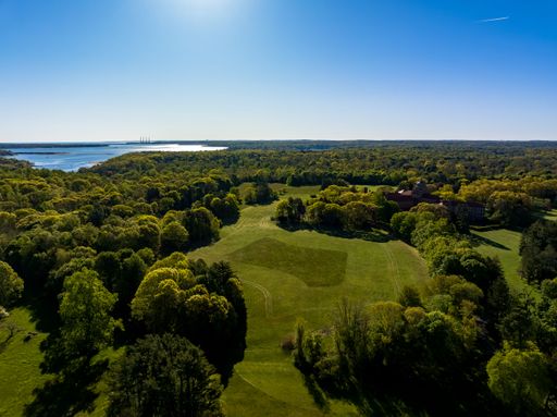 An aerial view, high over the green landscape on Long Island, New York on a sunny day with Oyster Bay in the background