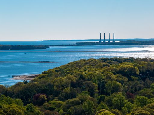 An aerial view, high over the green landscape on Long Island, New York on a sunny day with Oyster Bay in the background