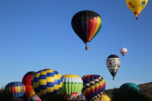 A colorful array of hot air balloons fills the sky at a festive outdoor gathering