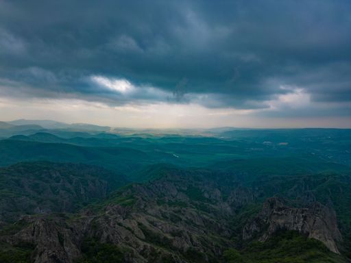 A picturesque scene of the majestic mountains of Georgia with a dramatic cloudy sky above them.