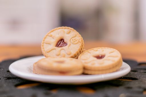 A selective focus of a plate of round cookies with red heart-shaped jelly in the middle