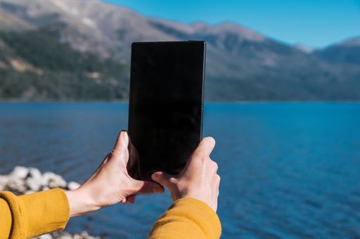 A closeup shot of a person  photographing the lake on a tablet