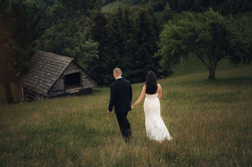 A young newlywed couple walking in a grassy field.