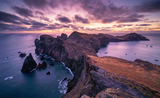 A breathtaking sunset is captured over tranquil water with rock formations in Madeira, Portugal