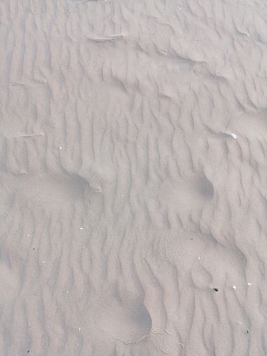 A top view of sand texture with slightly visible footprints on the surface