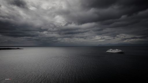 A boat sailing in the open water on a stormy day with grey clouds in the sky