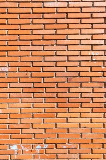 An orange brick wall with visible cracks and small scratches