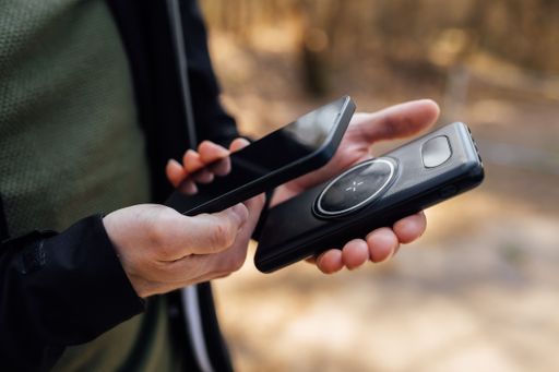 The closeup of the hands of a person holding a smartphone and a wireless phone charger