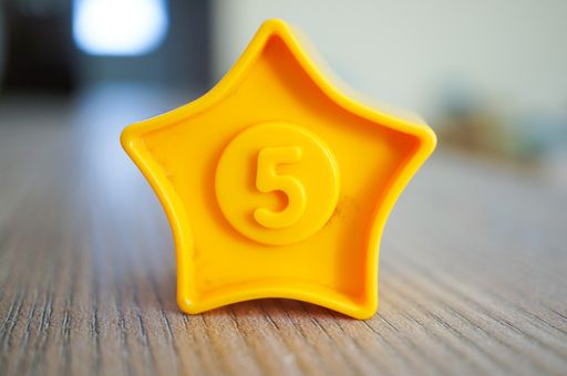 A closeup shot f a yellow star shaped plastic toy with the number five