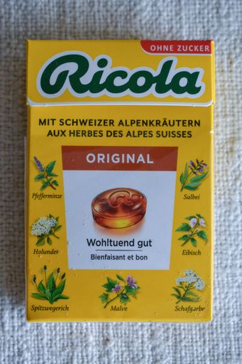 A colorful assortment of Ricola candies in their signature packaging resting on a wooden dining table