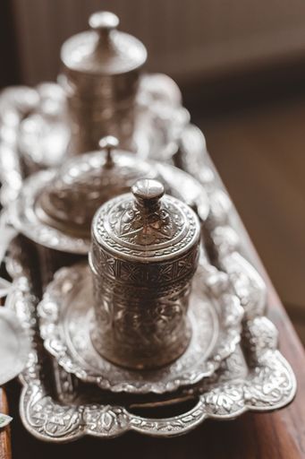 A vertical closeup shot of an antique silver tea set with a blurry background