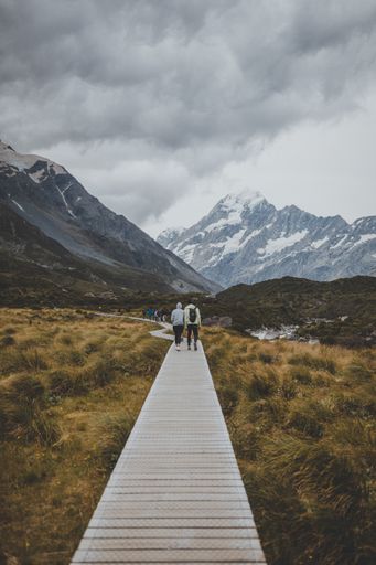 People in Hooker Valley Track with a view of Mount Cook in New Zealand