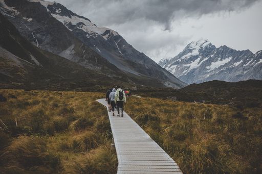 People in Hooker Valley Track with a view of Mount Cook in New Zealand
