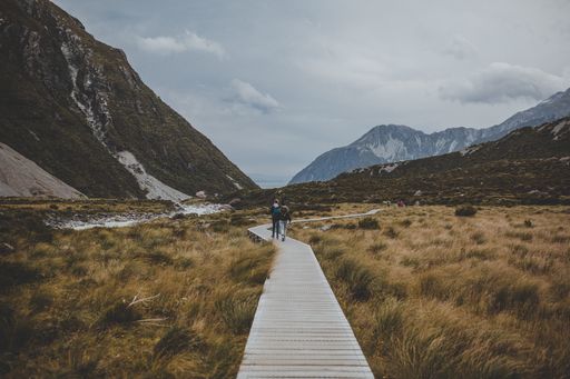 People in Hooker Valley Track with a view of Mount Cook in New Zealand