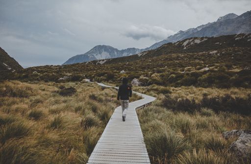 A man walking in Hooker Valley Track with a view of Mount Cook in New Zealand