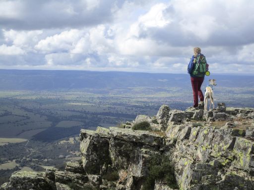A female hiker with her dog on top of a rocky mountain