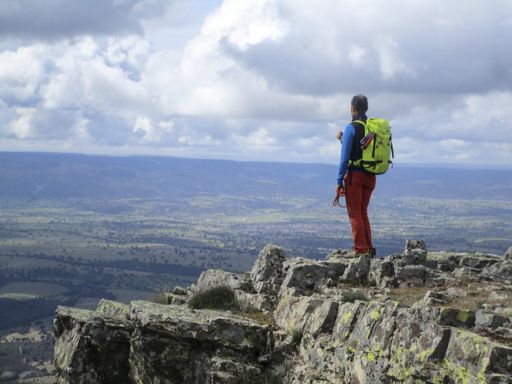 A young male hiker on top of a rocky mountain enjoying the scenic view