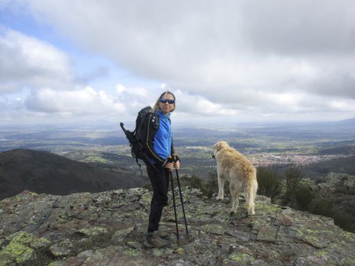 A female hiker with her dog on top of a rocky mountain