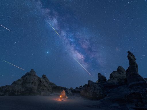 A stunning night sky featuring the Milky Way galaxy draped across a backdrop of two large desert rocks in the foreground