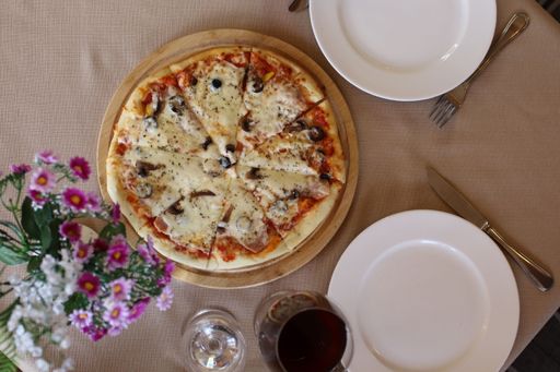 A delicious pizza and a bottle of red wine on a restaurant table