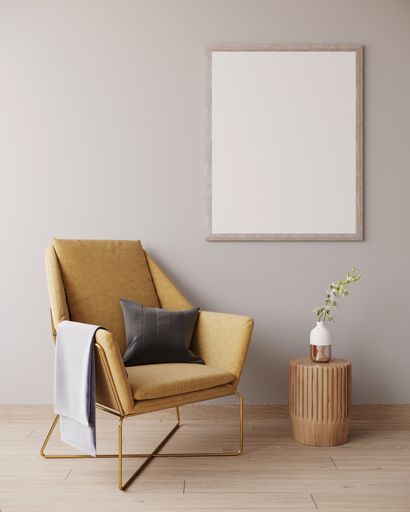 A yellow armchair in a light grey room against a white wall with a picture frame adjacent to it, providing a copy space