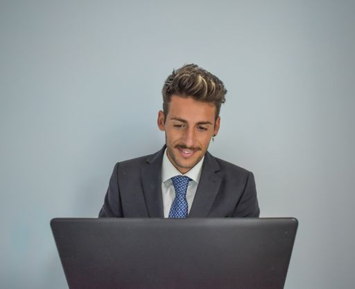 A young Spanish businessman in an elegant suit working on a laptop