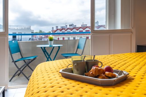 A tray with a cup of coffee and cookies for breakfast in a room on the bed