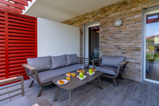 A cozy outdoor seating area with a wooden table with breakfast ready to be enjoyed