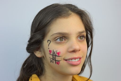 A closeup portrait of a young pretty girl from Serbia with tic tac toe drawn on her cheek