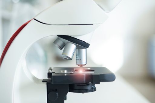 A closeup of a white microscope in a laboratory setting