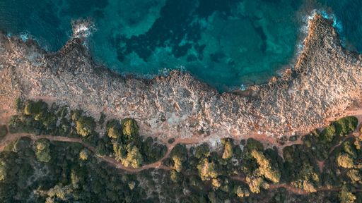An aerial shot of a stunning rocky coastline and brilliantly clear blue waters near Sa Coma in Mallorca Island, Spain