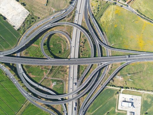 Aerial view of a four-lane highway intersection with a car driving along one of the lanes
